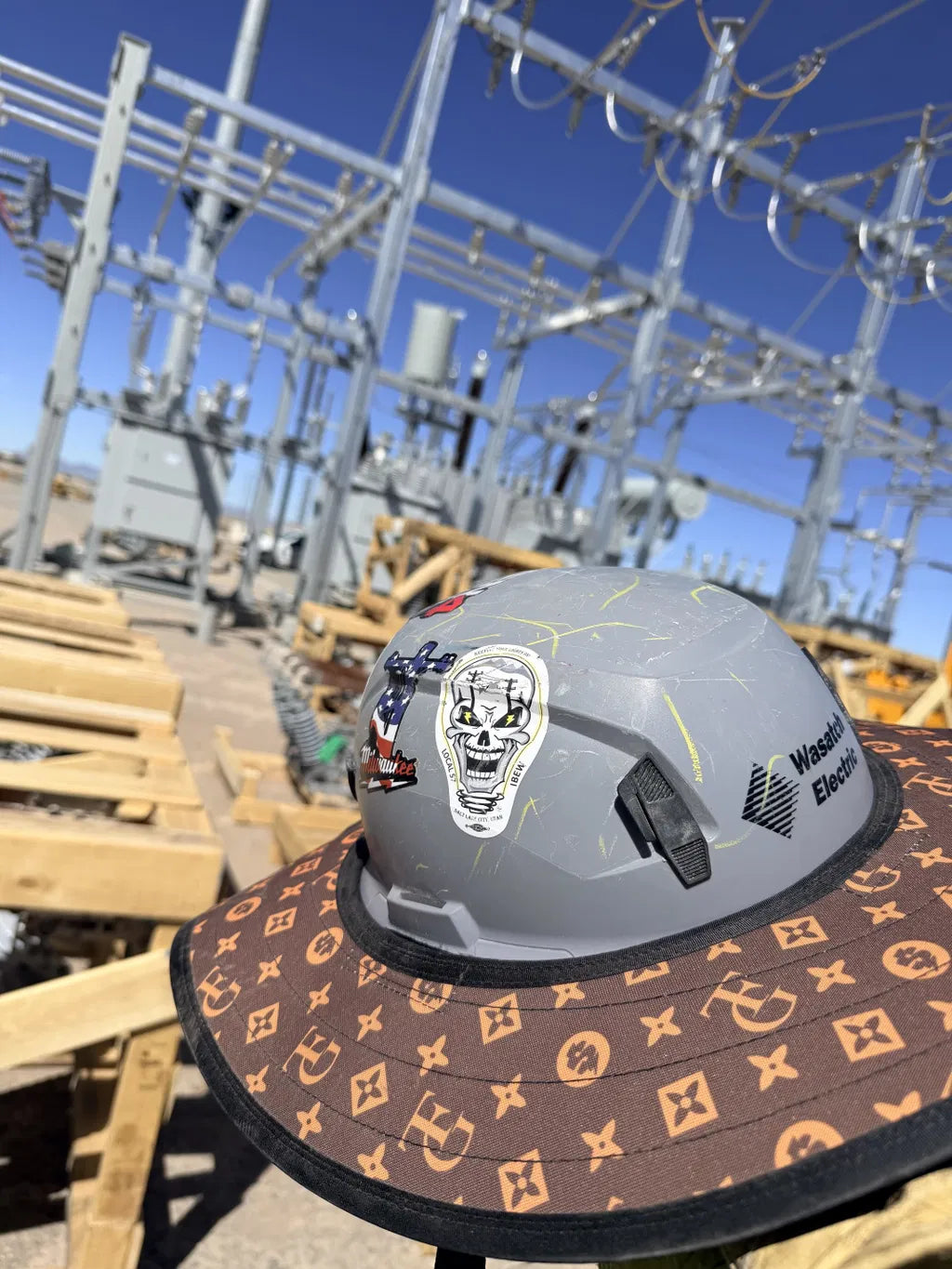 TG Brown Hard Hat Sun Shade Visor, mounted on a gray hard hat at an electrical substation