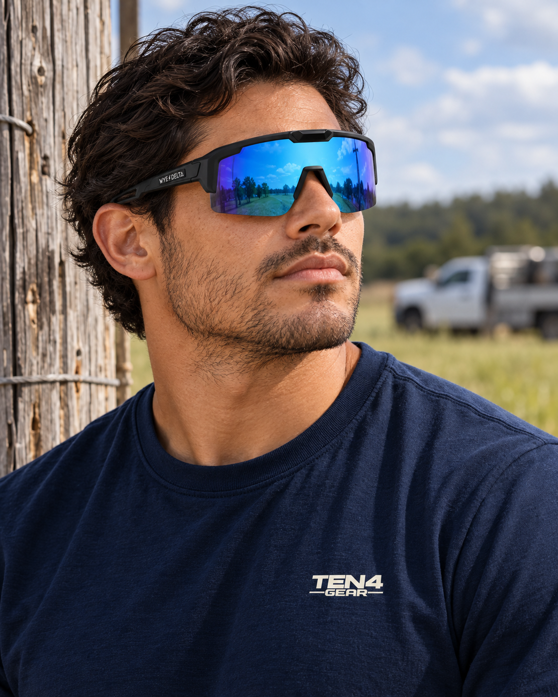 Lifestyle model mockup wearing Wye Delta REACTIV Blast sunglasses and navy TEN4 shirt outdoors.