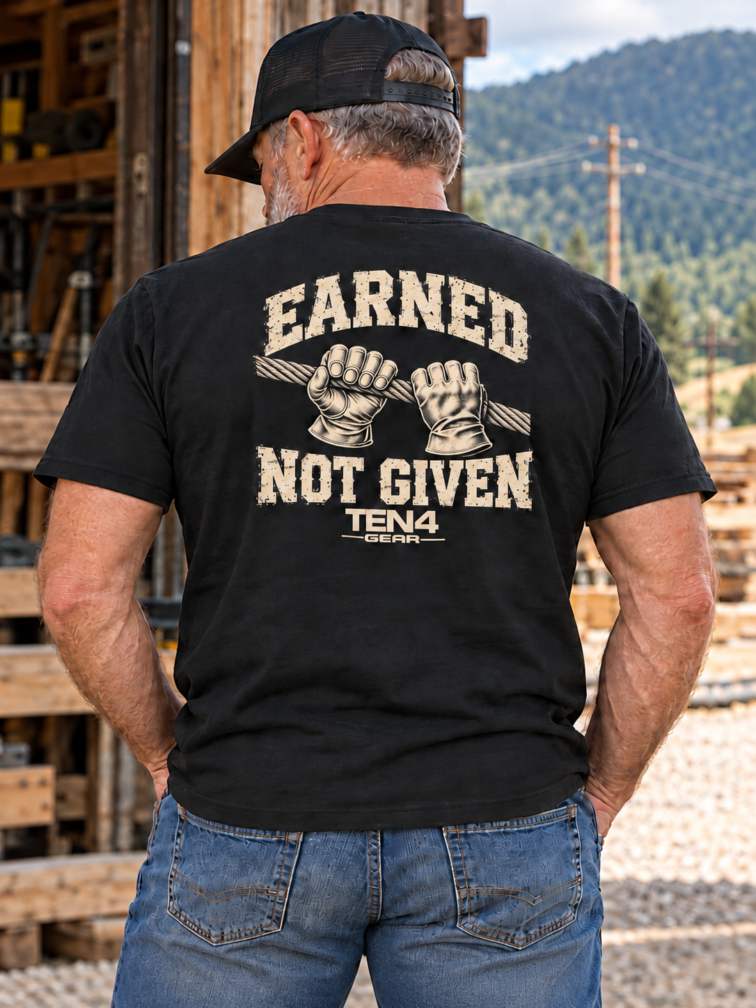 TEN4 Earned Not Given black tee, single rear-facing model in a mountain utility setting