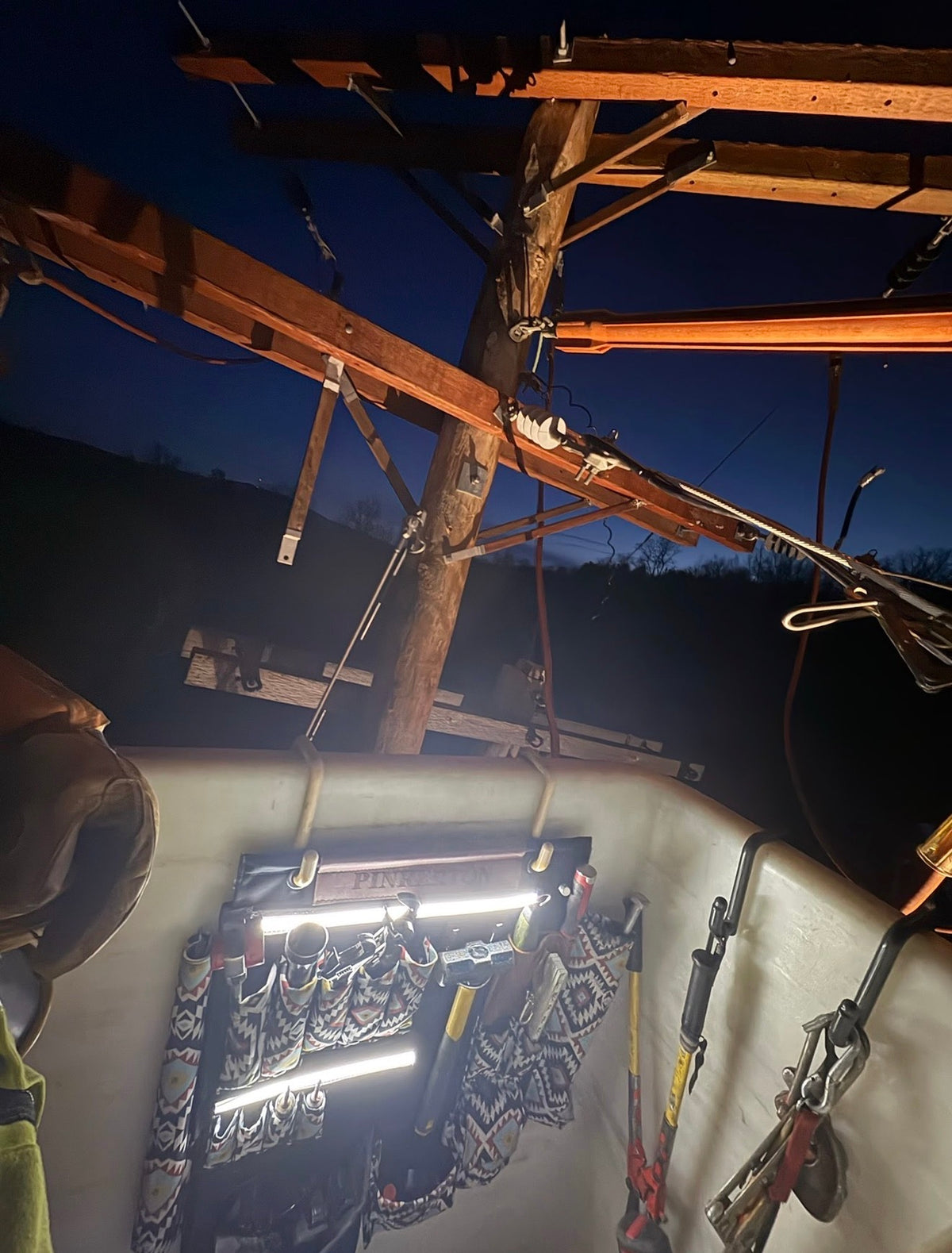 Original jobsite photo of a TEN4 G-Board loaded with tools inside a bucket at night, with both integrated LED strips illuminated. Tools and mounting hooks not included.