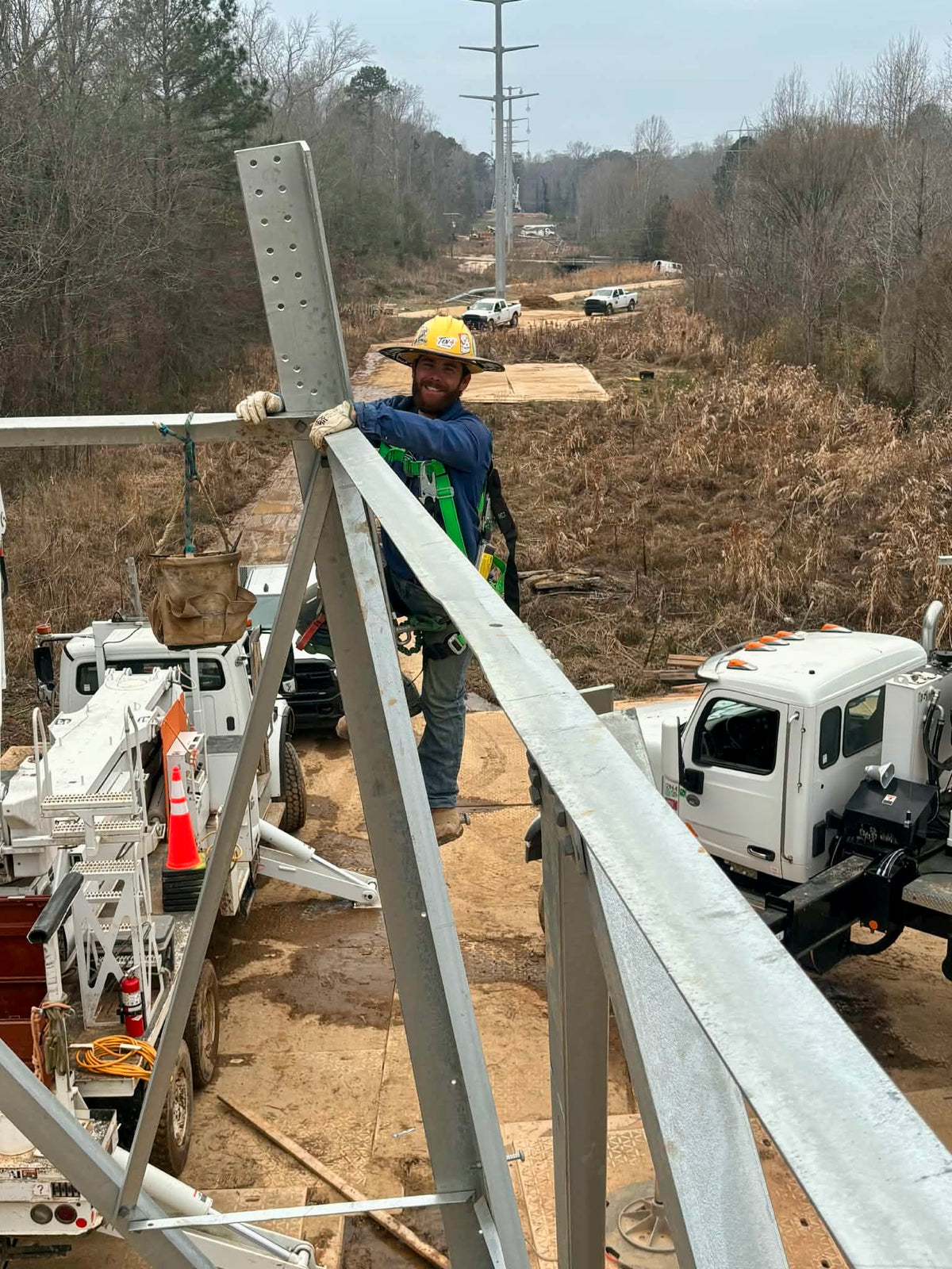 Matt, TEN4 Gear co-owner and lineman, wearing a TEN4 sunshade while working on a steel structure at a line-construction jobsite.