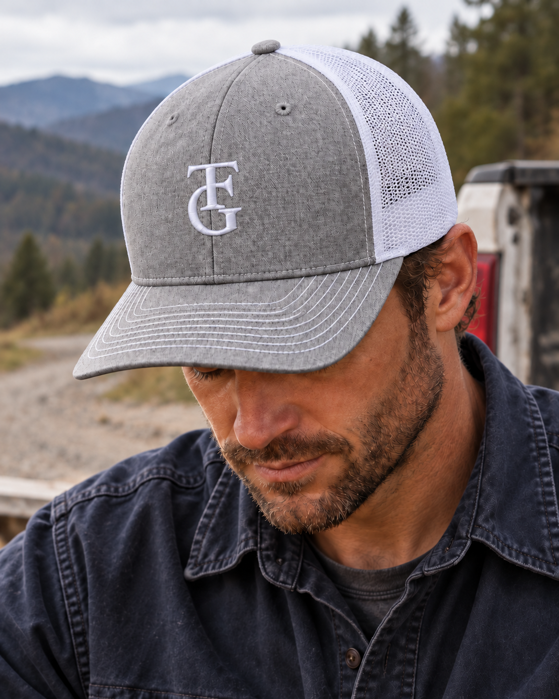 Heather gray and white TEN4 TFG hat with white embroidery, worn by a man in a navy work shirt looking down outdoors