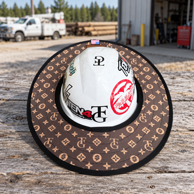 TG Brown sunshade on a white hard hat resting on a rustic workbench beside a utility workshop