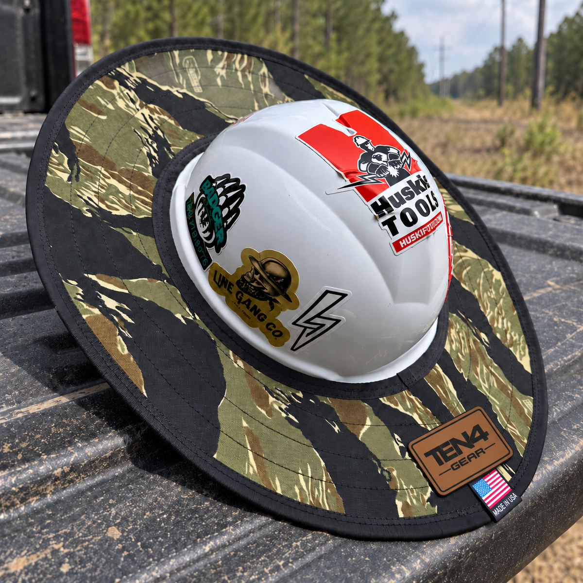 Tiger Stripe Camo sunshade on a hard hat with current TEN4 patch centered at the rear, on a pickup tailgate