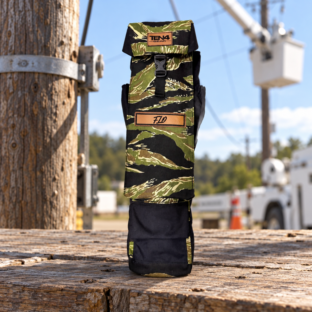 Tiger Stripe 29-inch Utility bag with formed buckle lid, side pockets and extra bottom pocket — original product photo; background edited to an outdoor utility jobsite.